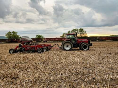 A tractor towing a piece of farm equipment through a field
